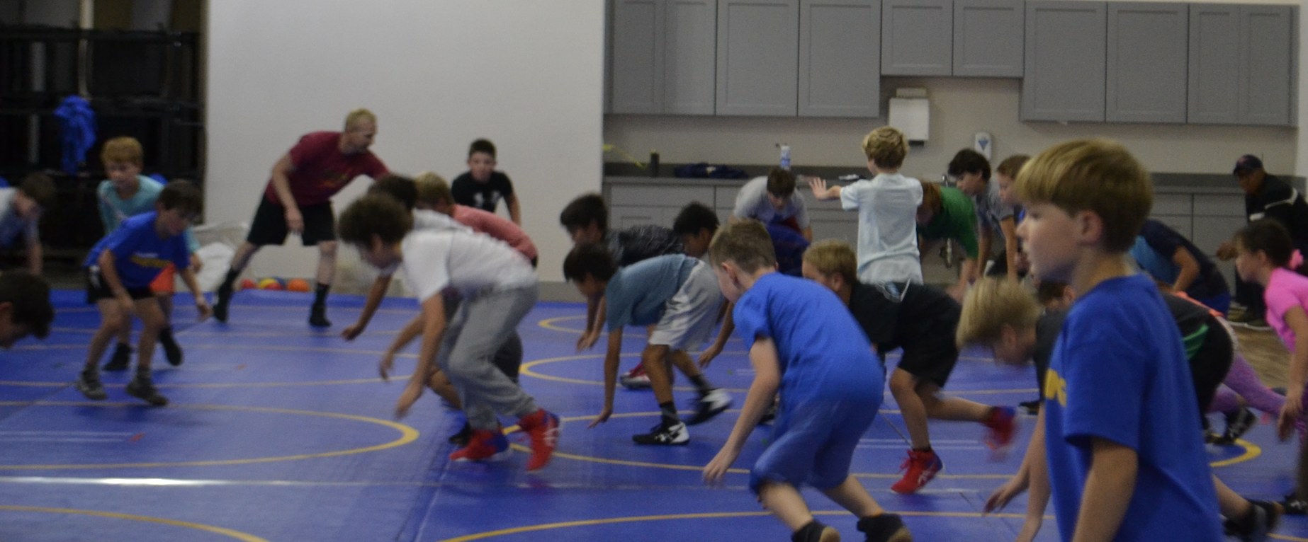 Kids practicing wrestling drills on the mat